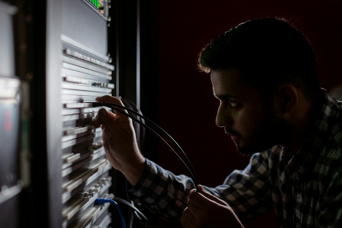 An engineer patching cables in an equipment rack