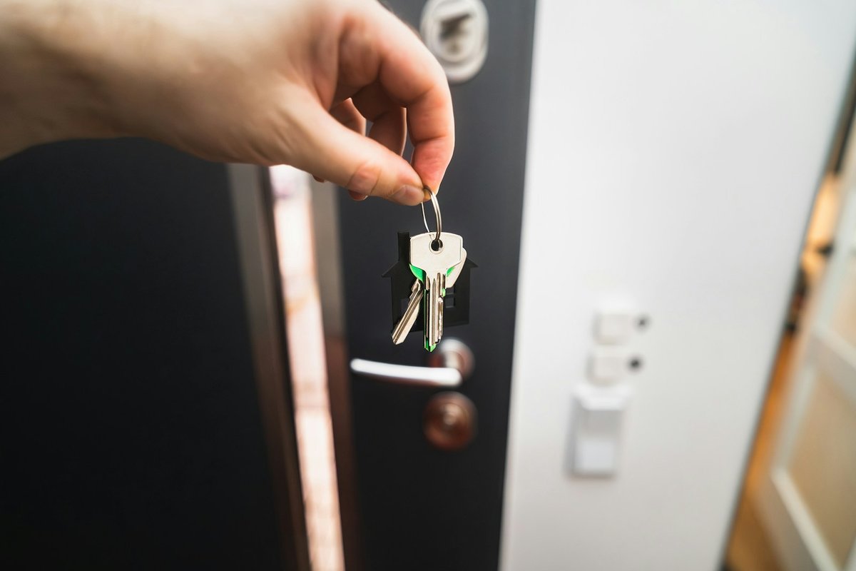 A hand holding up the keys at a front door